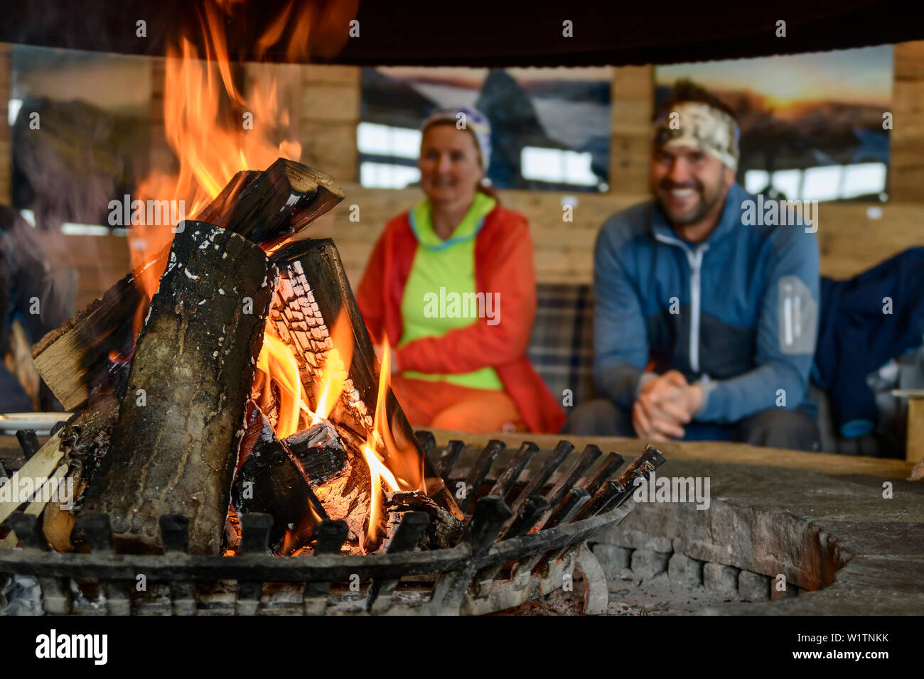 Burning logs in open fire, man and woman out of focus in background, ski arena Kaltenbach, valley of Zillertal, Tuxer Alps, Tyrol, Austria Stock Photo