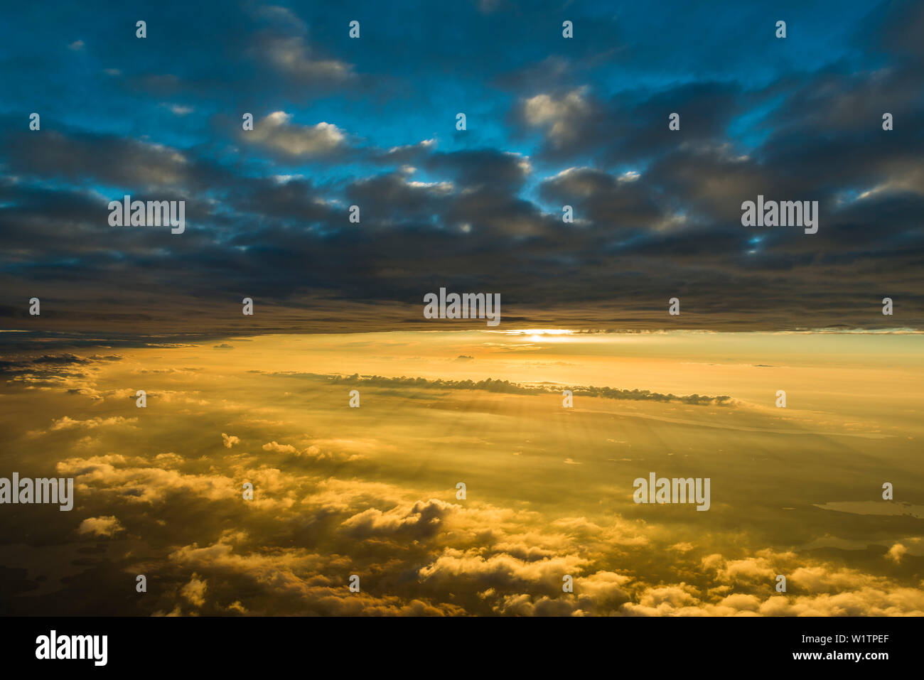 a thin layer of clouds devides the blue sky from the warm light of the ...