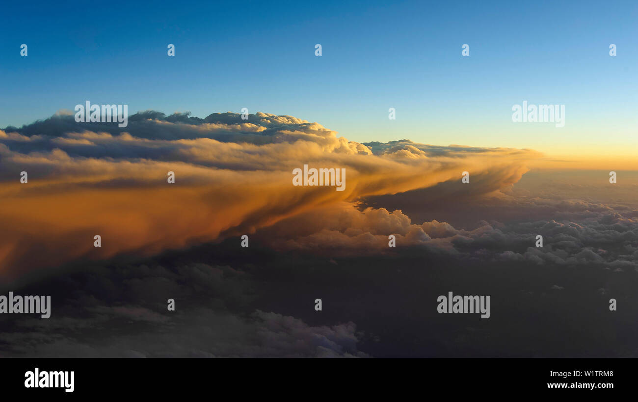 warm light in the evening hits a large cloud formation above Switzerland Stock Photo