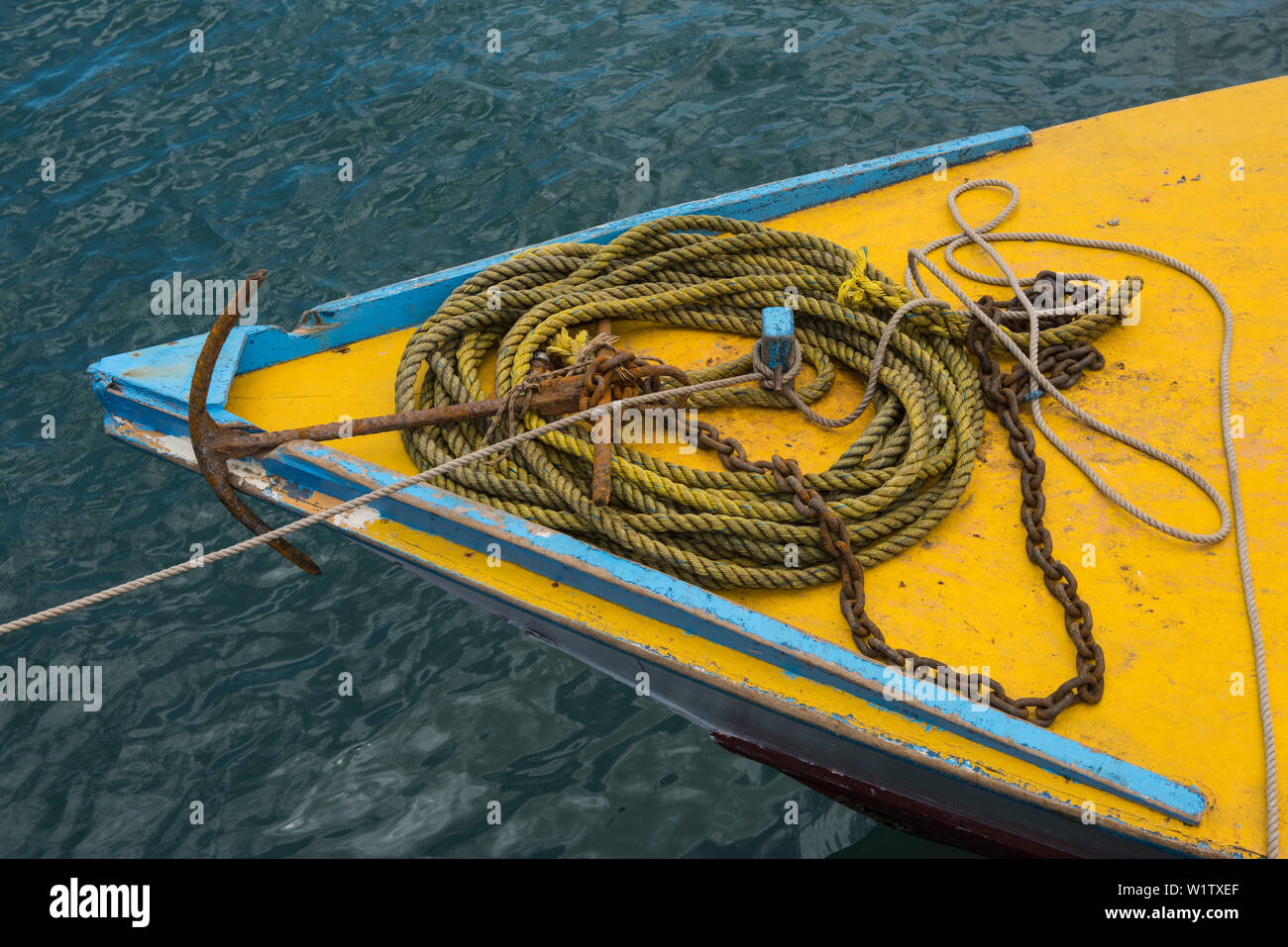 A yellow and blue bow of a small ship is strewn with yellow rope attached to a rusty chain and anchor, Lautoka, Viti Levu, Fiji, South Pacific Stock Photo