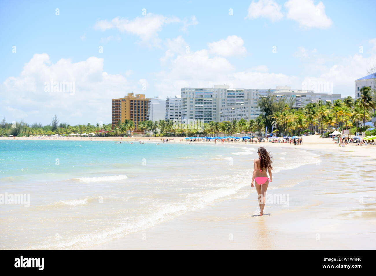 People on Isla Verde resort beach in Puerto Rico. Unrecognizable woman walking down the beach on summer holiday in bikini on famous Hispanic travel destination. Stock Photo
