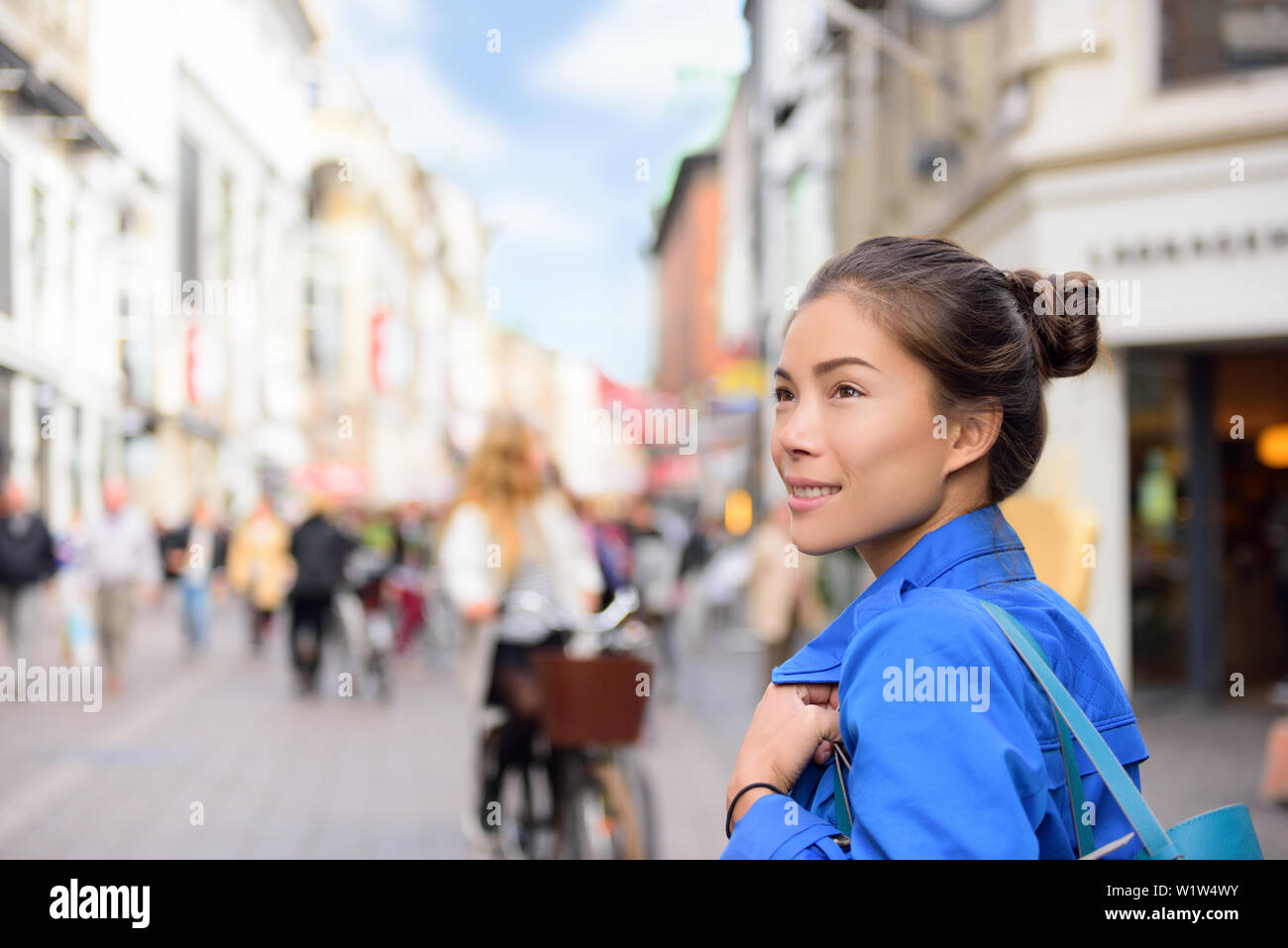 Shopping woman lifestyle in Copenhagen street. Scandinavian travel, tourist adult alone walking looking at shops during fall or spring in famous European city center in Denmark. Stock Photo