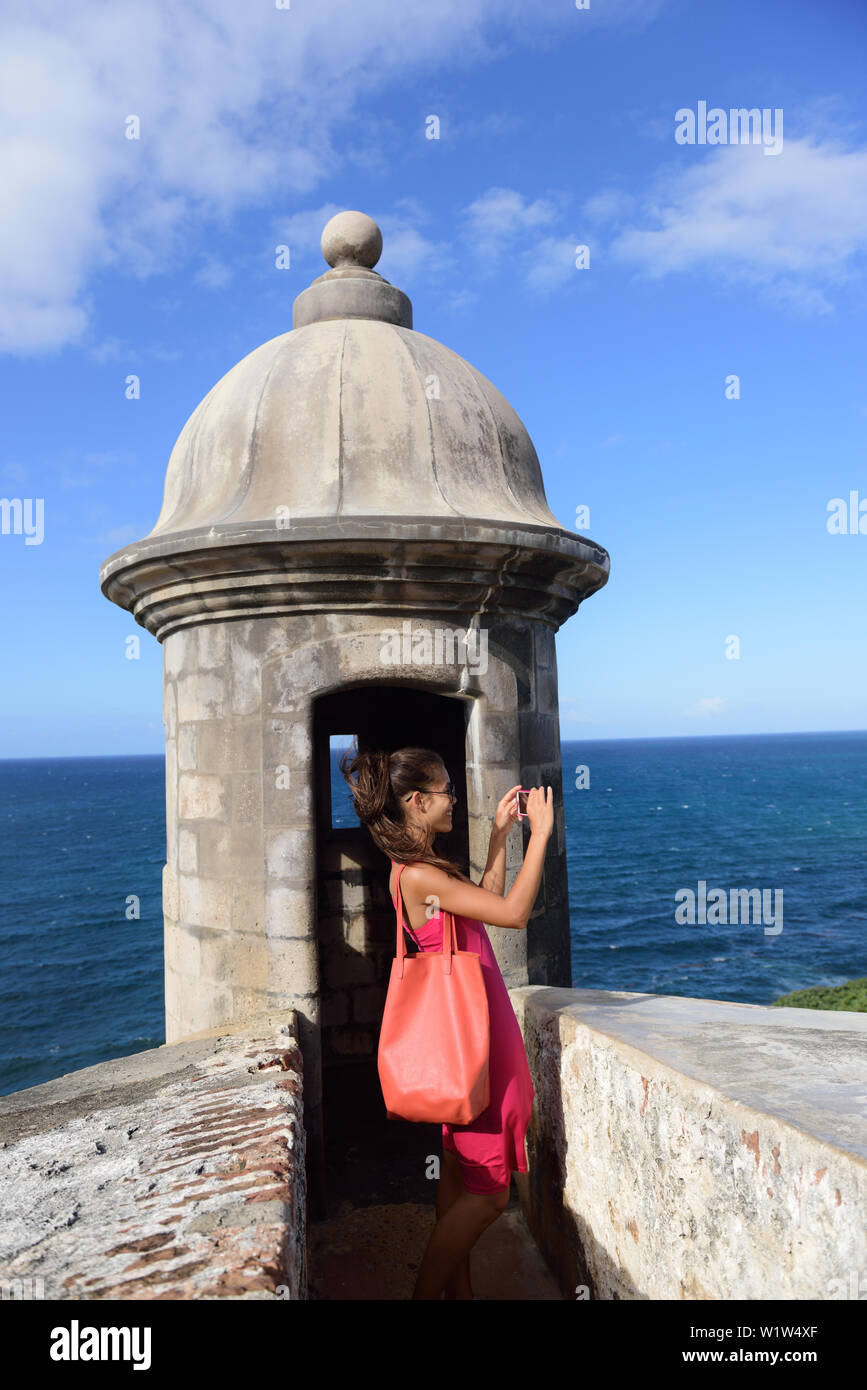 Puerto Rico woman taking pictures with smartphone at Old San Juan Fort Castillo San Felipe Del Morro. Asian tourist on her american travel visiting a famous landmark during summer vacations. Stock Photo