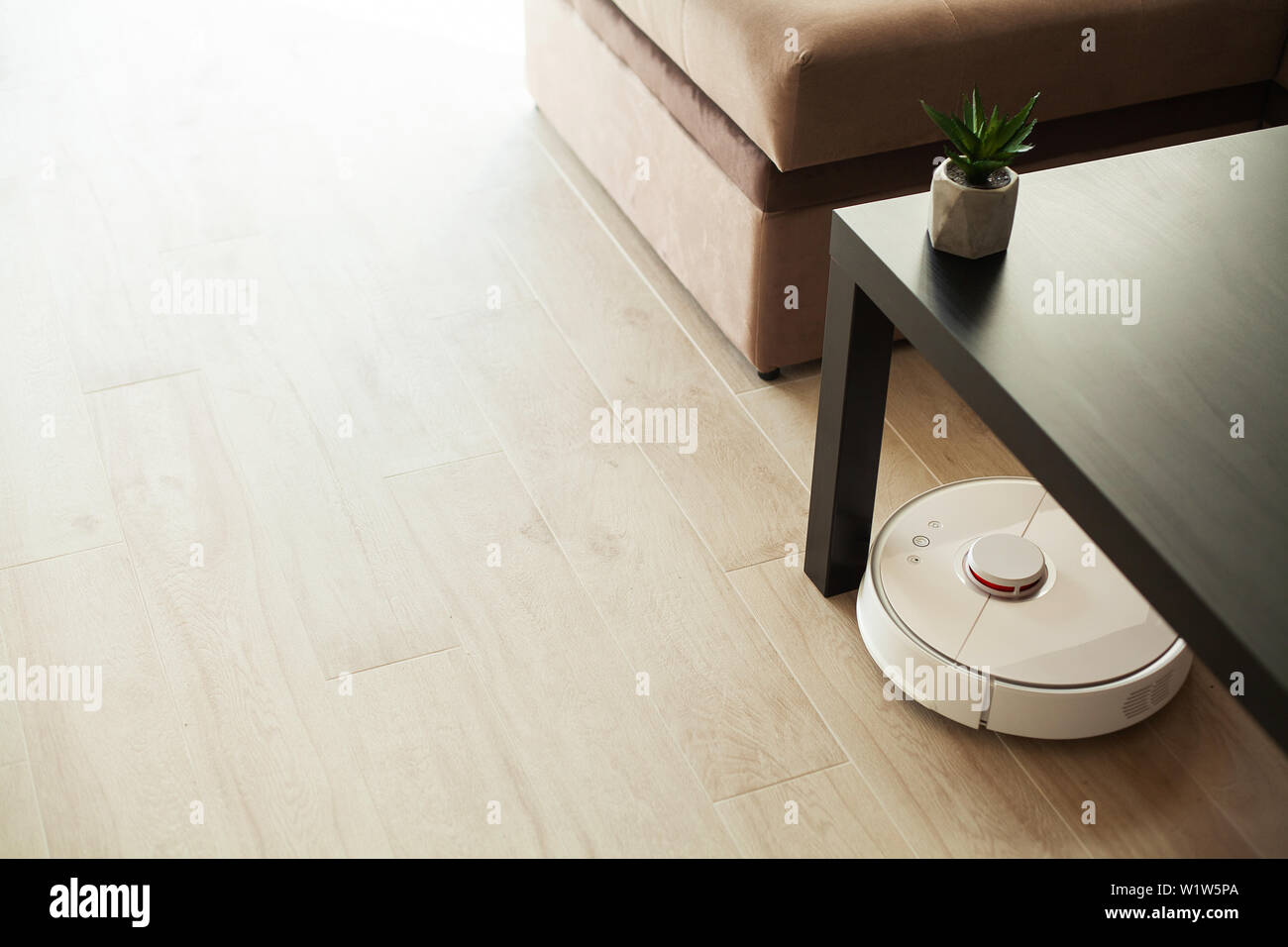 Smart House. Vacuum cleaner robot runs on wood floor in a living room