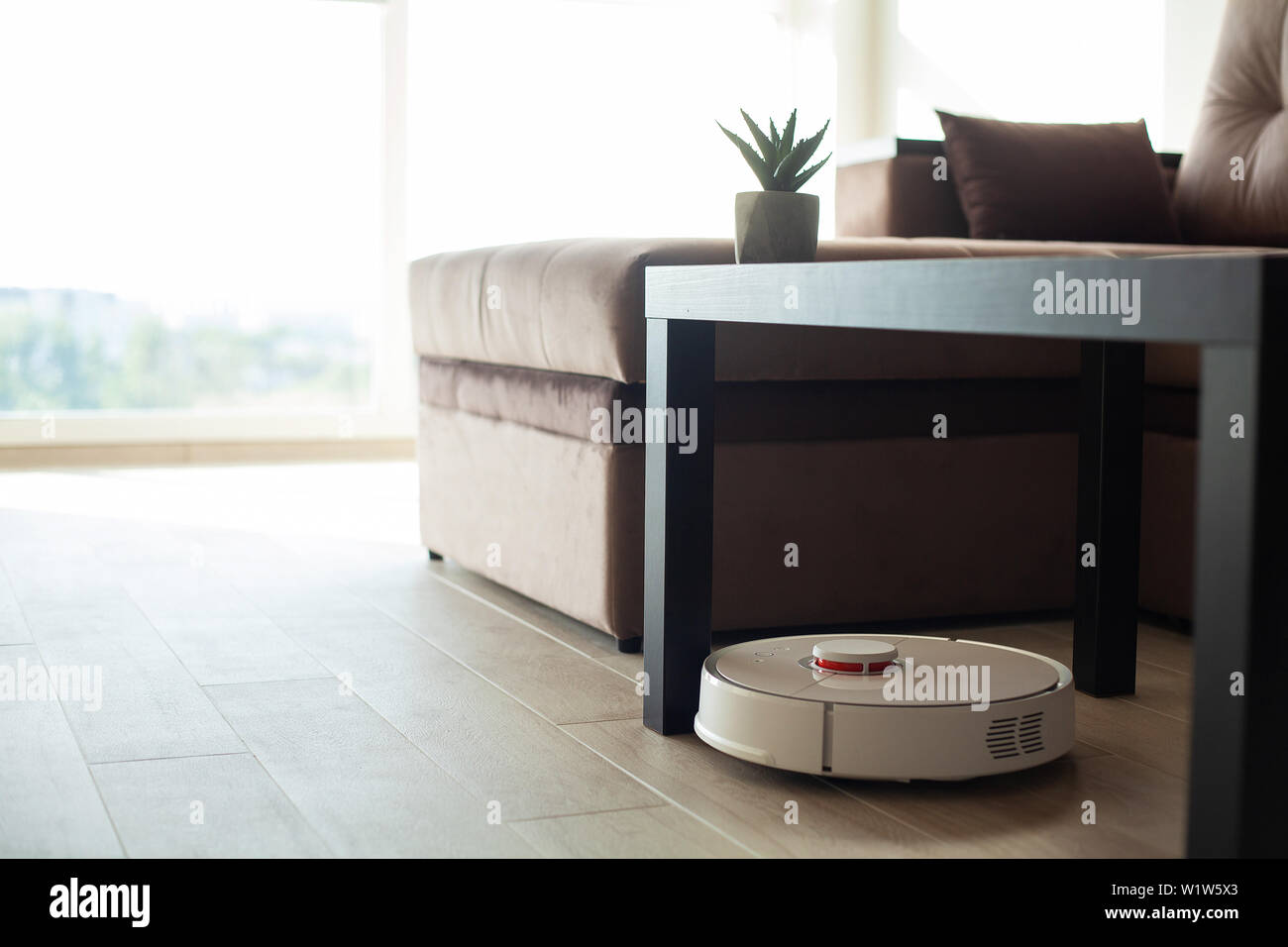 Smart House. Vacuum cleaner robot runs on wood floor in a living room ...