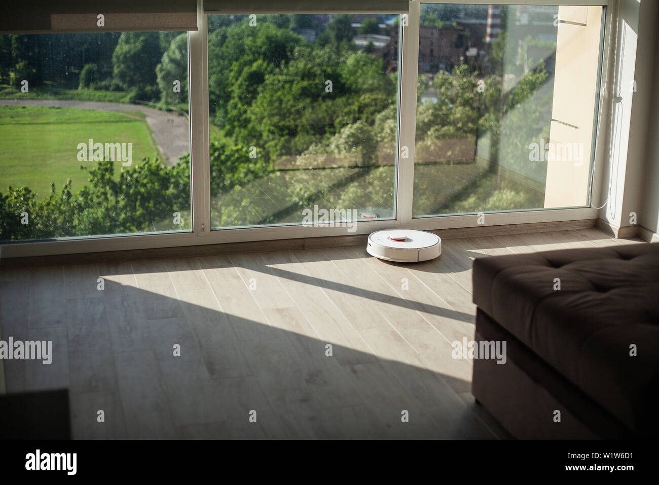 Smart House. Vacuum cleaner robot runs on wood floor in a living room ...