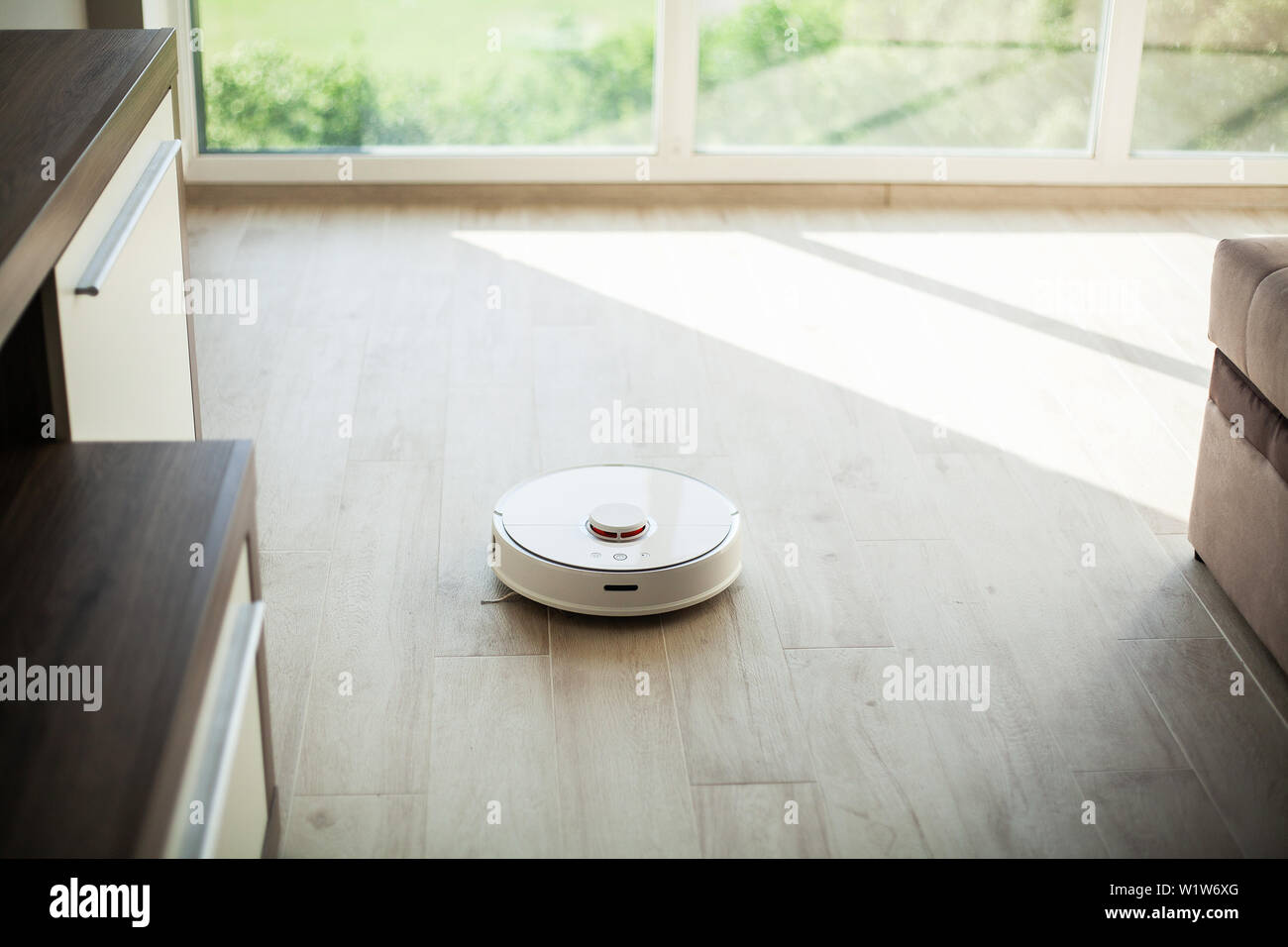 Smart House. Vacuum cleaner robot runs on wood floor in a living room ...