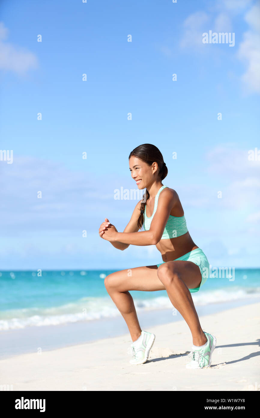 Fitness woman doing bodyweight workout training calves with plie squat calf raise exercise. Asian sport girl doing a ballet inspired ballerina pose to activate glutes and lower body by raising heels. Stock Photo
