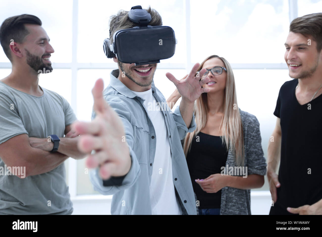 Young handsome man wearing virtual reality goggles touching controls to shoot in game Stock Photo