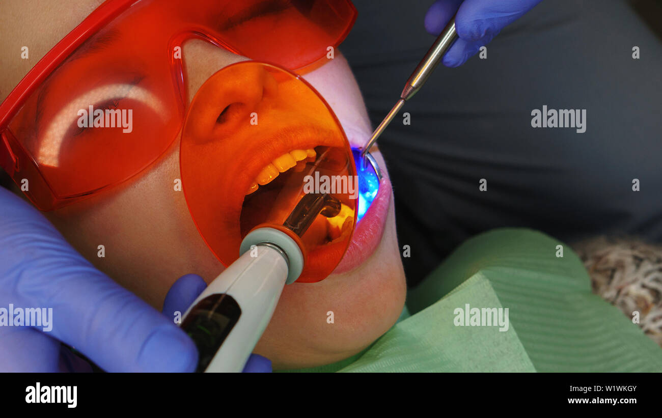 Dentist makes dental filling patient girl. Dental treatment. Acute pain