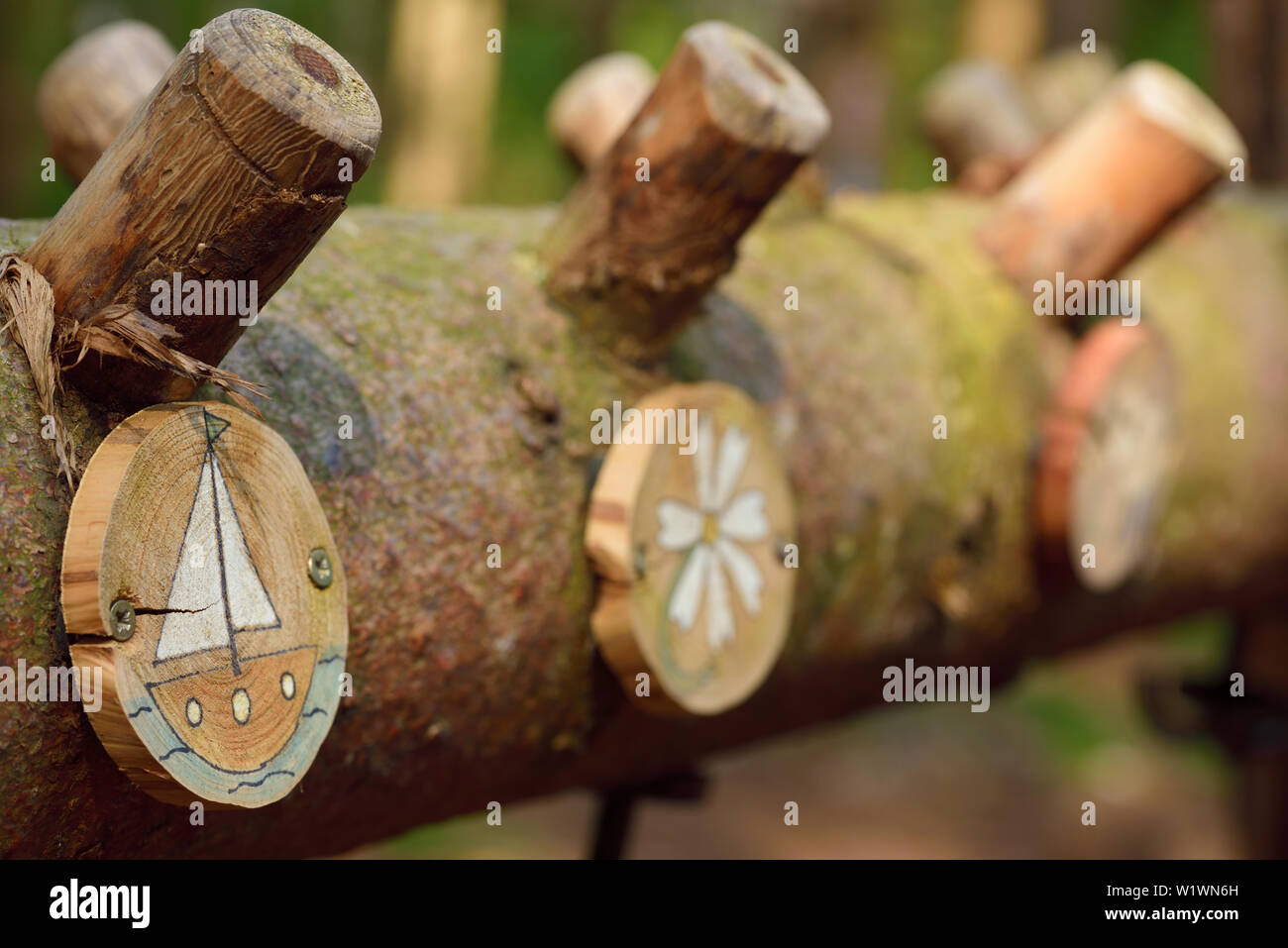 Rustic wardrobe with coat hooks and colorful simple name tags in the forest from a tree trunk Stock Photo