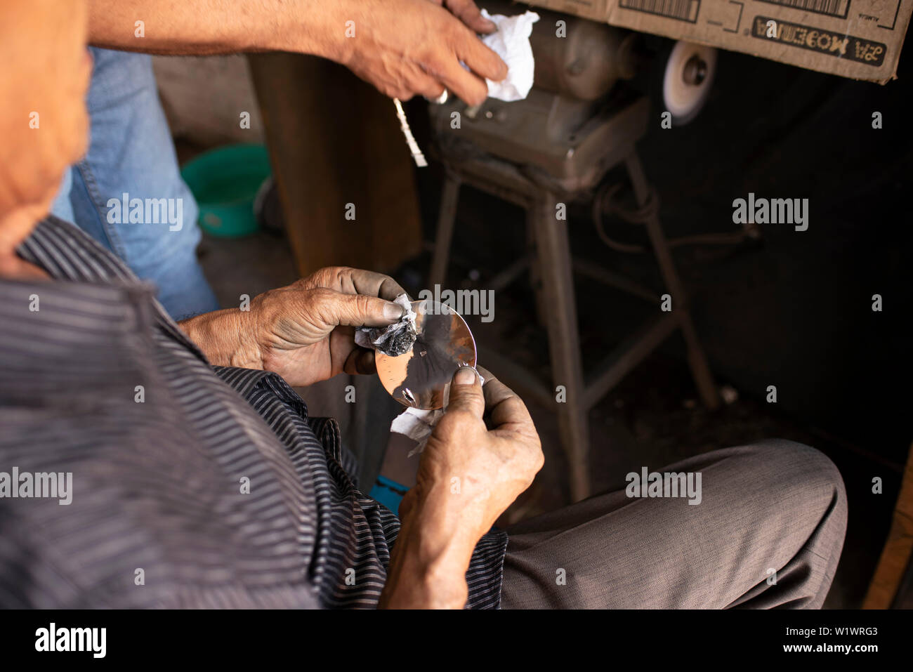 Local silversmith polishing silver plate with a cloth at a local workshop in Taxco, Guerrero, Mexico. Jun 2019 Stock Photo