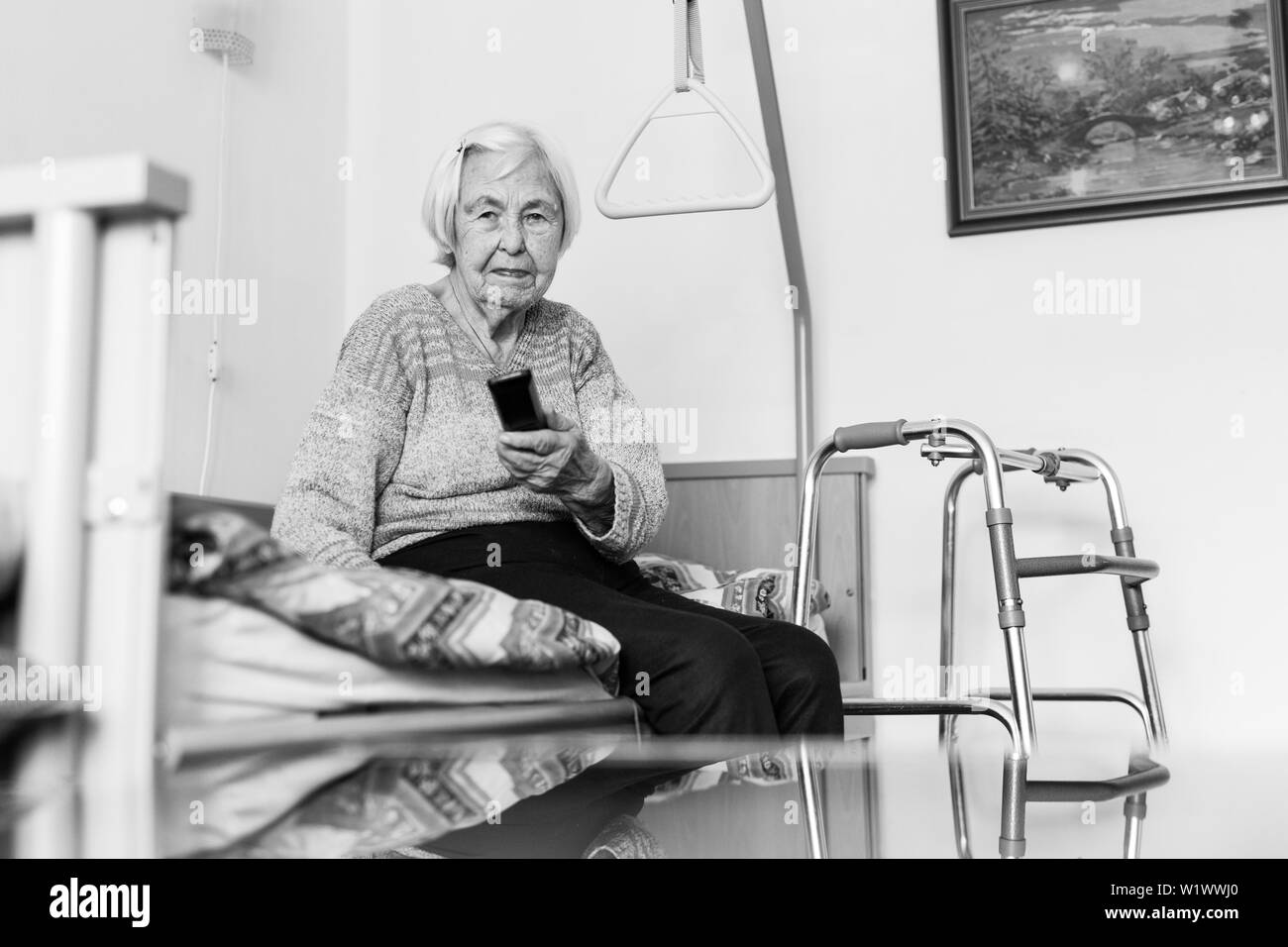 Elderly 96 years old woman operating TV or DVD with remote control Stock Photo