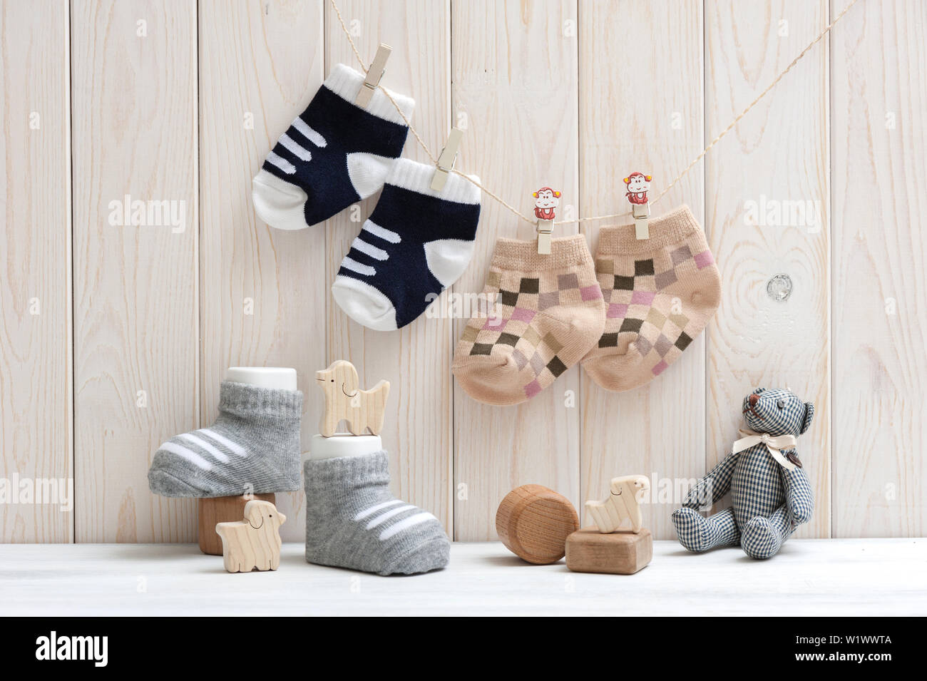 new baby socks hanging on clothesline over wood background, newborn and