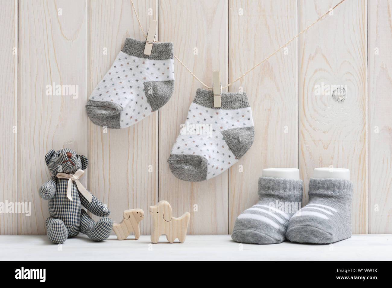 new baby socks hanging on clothesline over wood background, newborn and