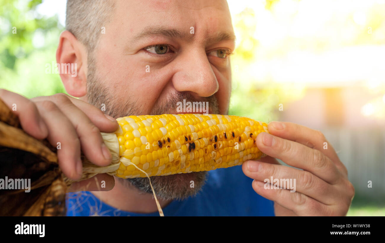 Man eating roasted corn on a cob Stock Photo