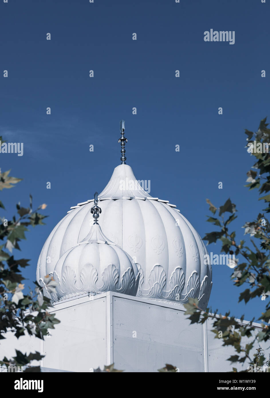 White cupolas of a Sikh Temple or Gurdwara with blue sky in the background Stock Photo