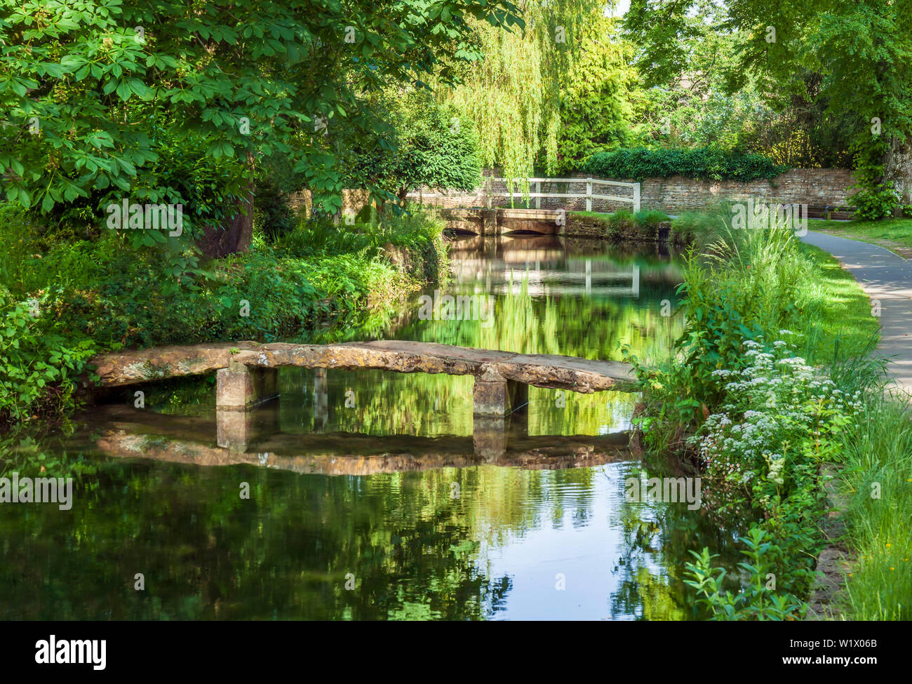 Old stone footbridge crossing the river Eye, in Lower Slaughter, Cotswolds, Gloucestershire, England, UK. Stock Photo