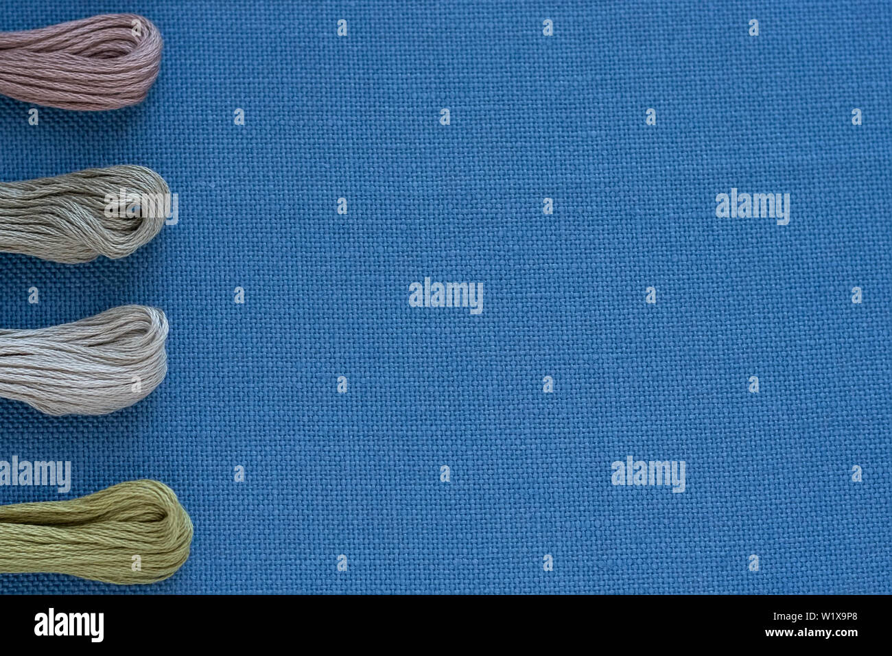 Multi-colored threads for embroidery on blue canvas. Place for text Stock Photo