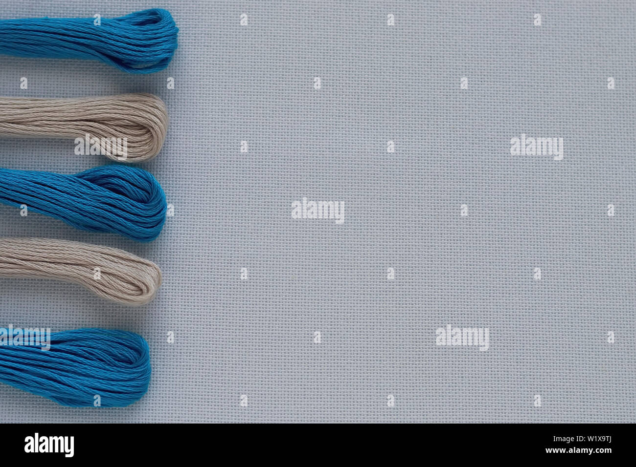 Multi-colored threads for embroidery on blue canvas. Place for text. Stock Photo