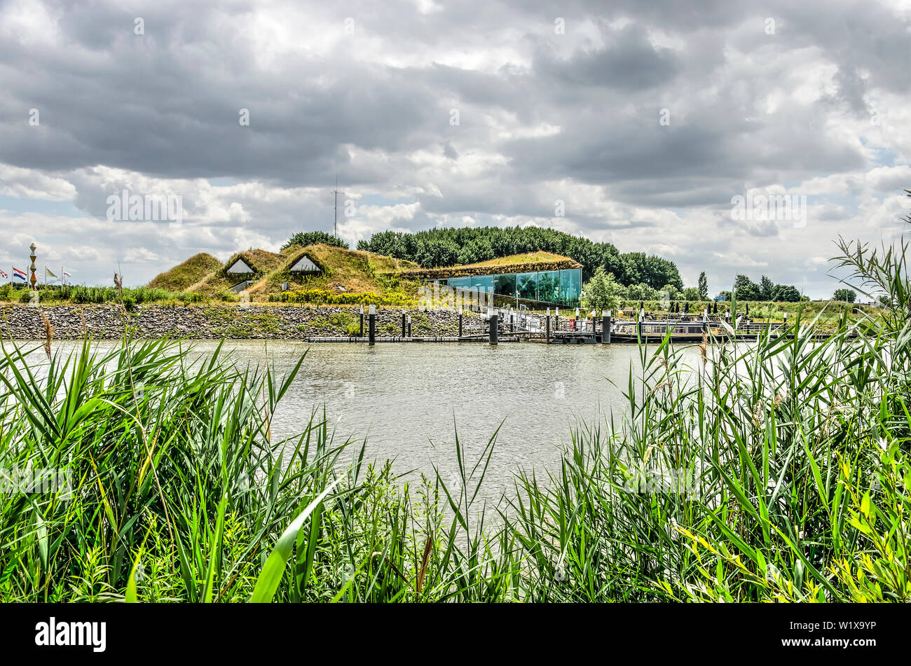 Werkendam, The Netherlands, July 3, 2019: view between reeds across the water towards the soil-covered Biesbosch museum, restaurant and jetty Stock Photo