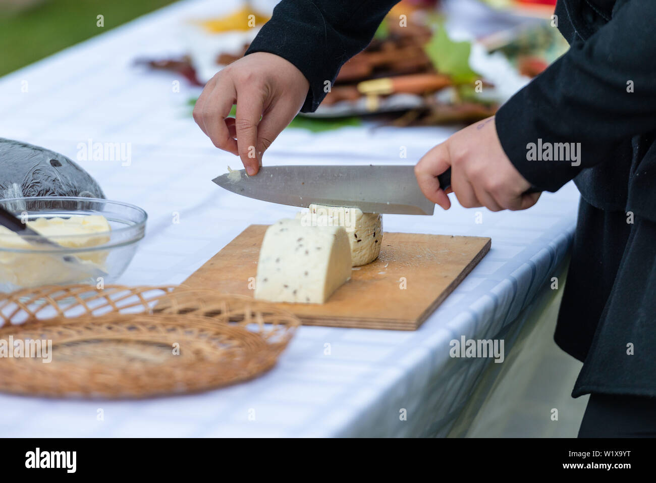 Worker slicing the cheese. Close up of  hands cut with a knife cheese - Image Stock Photo