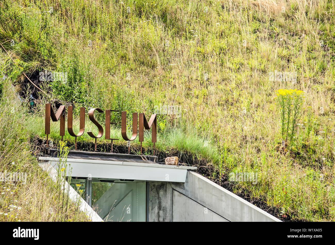Werkendam, The Netherlands, July 3, 2019: corten steel letters surrounded by grass and wildflowers indicate the entrance to the Biesbosch museum Stock Photo