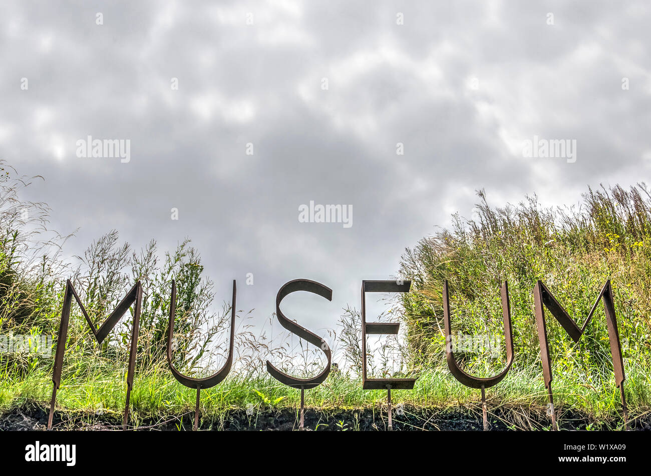 Werkendam, The Netherlands, July 3, 2019: corten steel letters spell the words museum surrounded by grass and wildflowers in Biesbosch national park Stock Photo