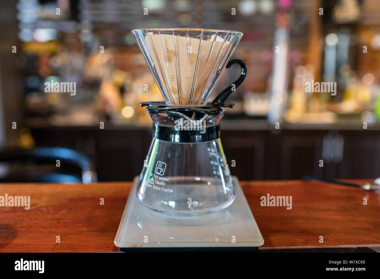 Measuring coffee drip with glass mug and paper filter on counter bar Stock Photo