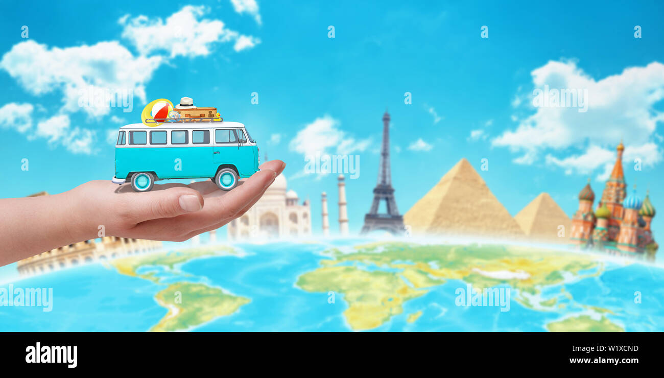 Old blue camper in hand. World sights and globe in background. Travel around the world concept. Stock Photo