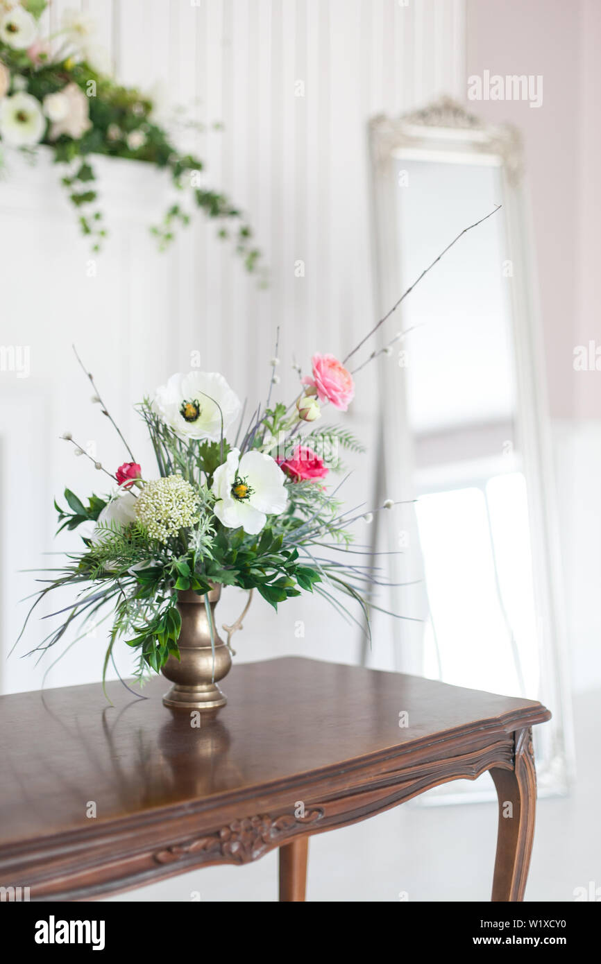 A bouquet of artificial flowers in a vase in the luxurious interior of the room. Soft focus. Stock Photo