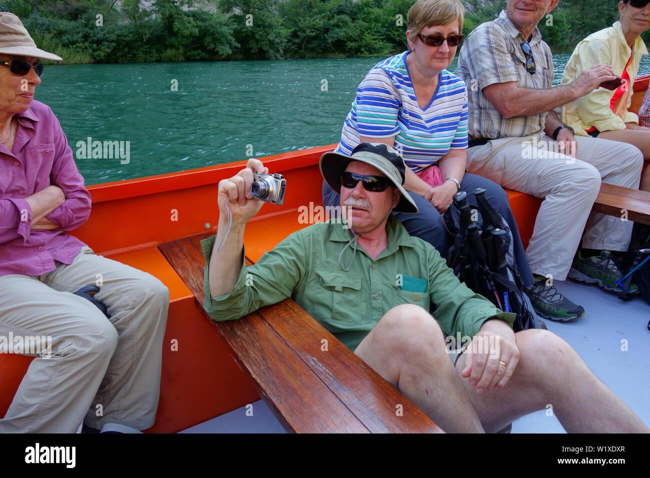 Man Trying to take a better picture by sitting on the bottom of a boat. Stock Photo