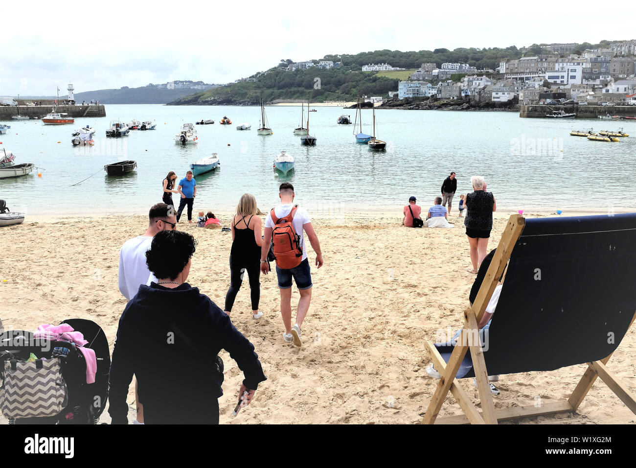 St. Ives, Cornwall, UK. June 24, 2019. Holidaymakers enjoying the sands overlooking the Harbor with high tide at St. Ives in Cornwall, UK. Stock Photo