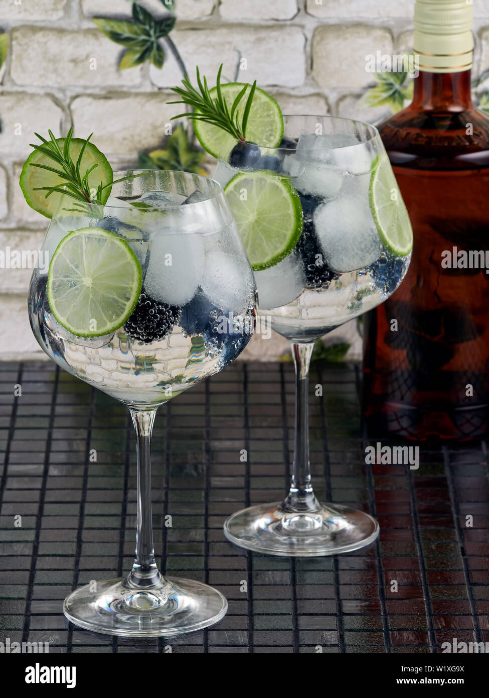 Gin tonic decorated with a rosemary sprig, fresh berries and slices of