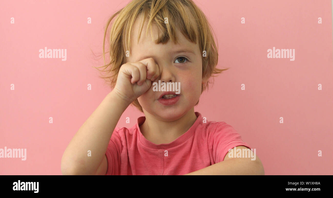 Cute child rubbing eye with plump hand Stock Photo