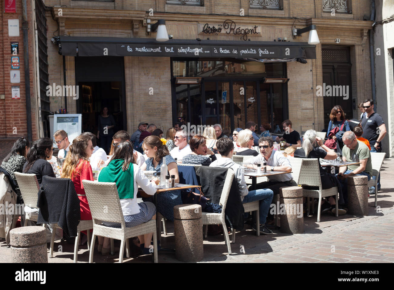 People enjoying eating lunch outside on the pavement at Le Bistro Le Regent, Place Saint-Georges, Toulouse, Occitanie, France Stock Photo