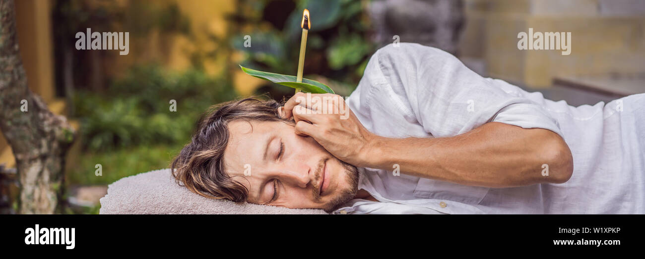 man having an ear candle therapy against the backdrop of a tropical