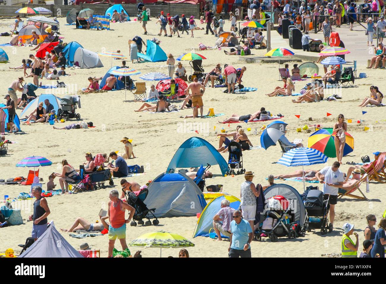 Lyme Regis, Dorset, UK.  4th July 2019. UK Weather.  Sunbathers on the beach at the seaside resort of Lyme Regis in Dorset enjoying a day of clear skies and scorching hot sunshine.   Picture Credit: Graham Hunt/Alamy Live News Stock Photo