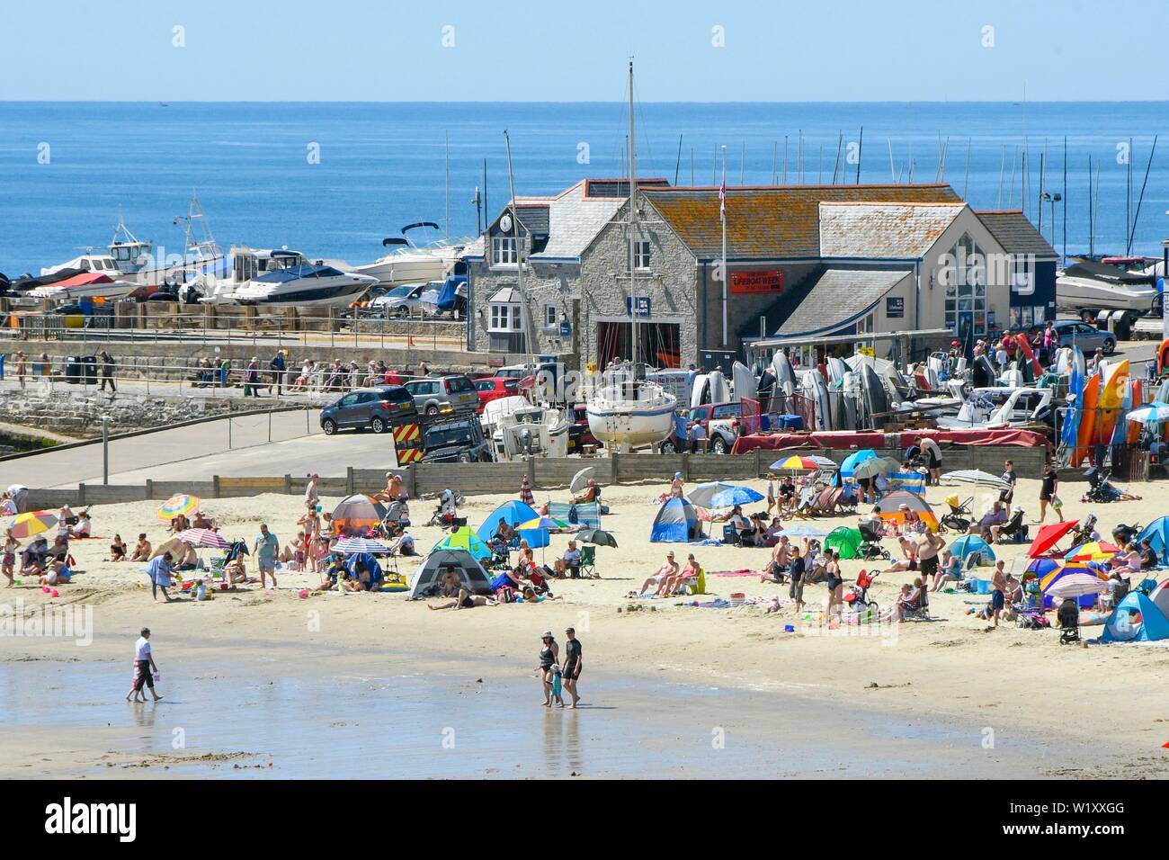 Lyme Regis, Dorset, UK.  4th July 2019. UK Weather.  Sunbathers on the beach at the seaside resort of Lyme Regis in Dorset enjoying a day of clear skies and scorching hot sunshine.   Picture Credit: Graham Hunt/Alamy Live News Stock Photo