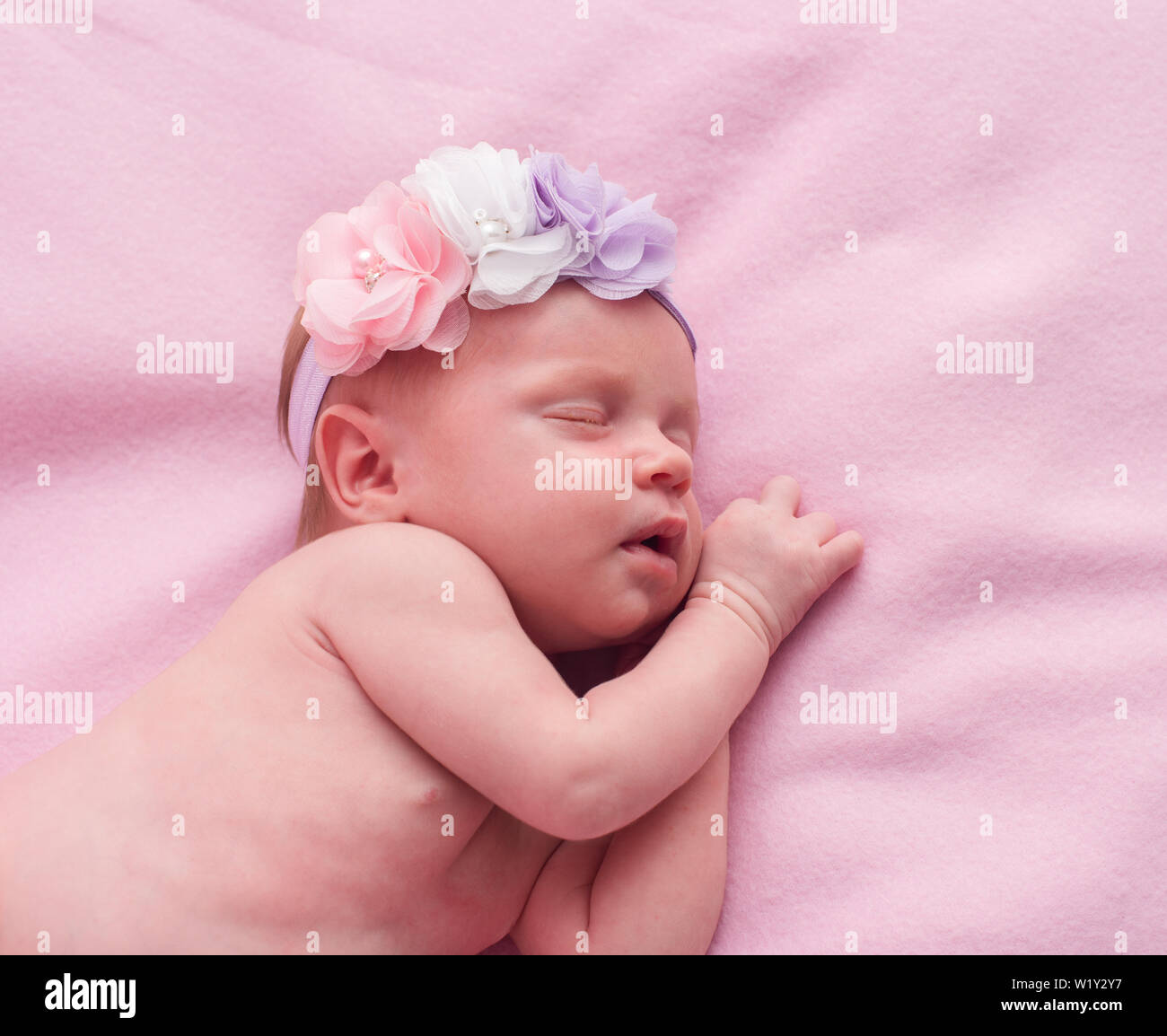 newborn baby girl sleeping with flowers on her head Stock Photo