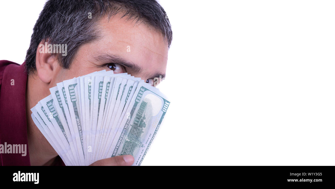 Man holding a widespread of one hundred dollar bills covering his face looking directly at camera greedy lustful satisfied victorious copy space negat Stock Photo