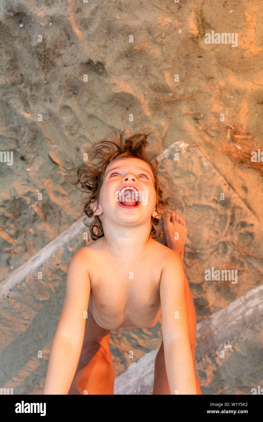 Happy young child boy girl playing with parent mother father on beach top view from above grimacing smiling cheerful Stock Photo