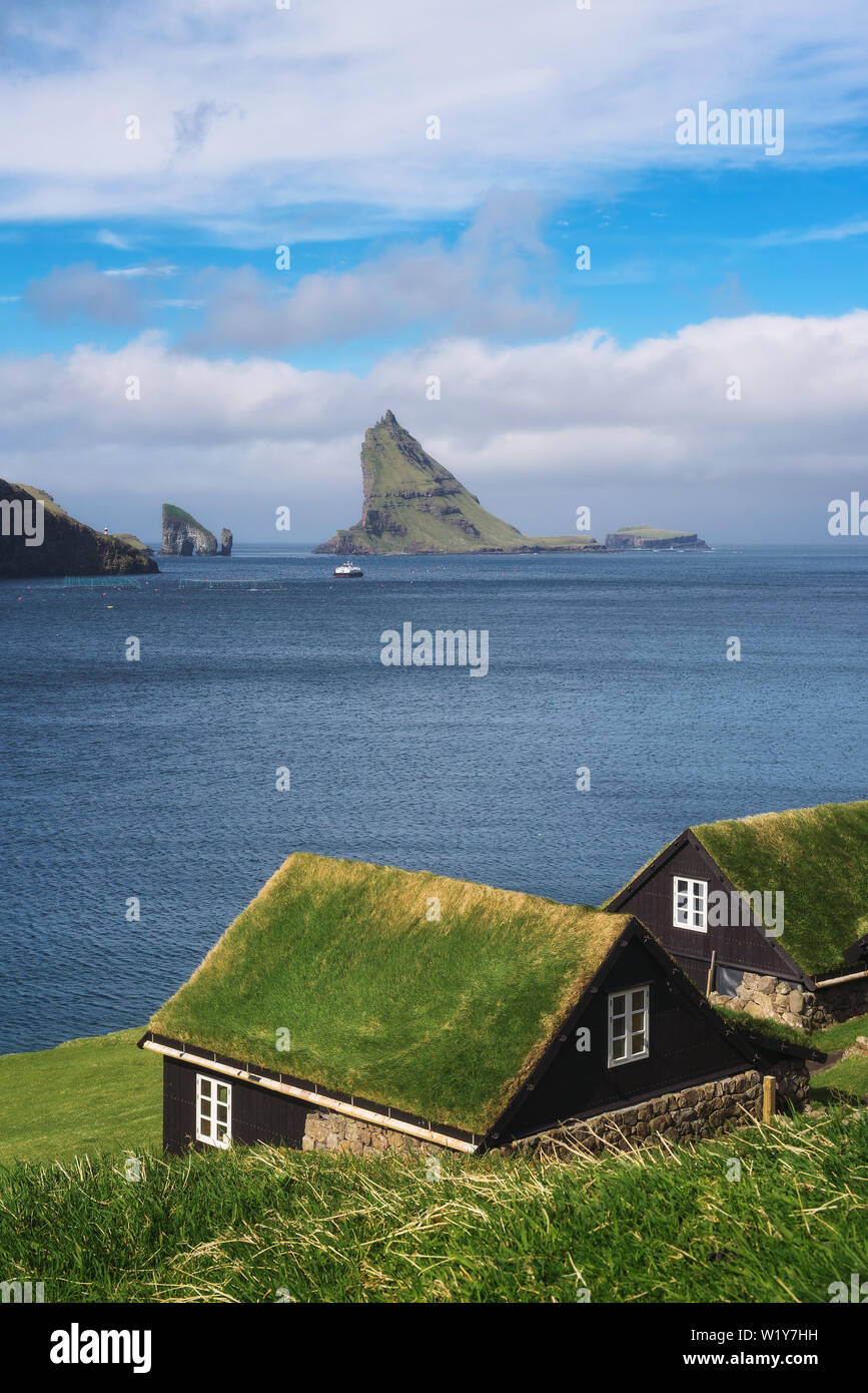 Houses on the coast of Faroe Islands with Drangarnir sea stack in the background Stock Photo