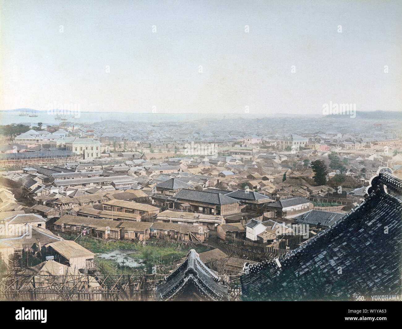 [ 1880s Japan - View of Yokohama ] —   Panoramic view of Yokohama sometime around 1881 (Meiji 14) as seen from Narita-san Enmei-in Temple (成田山横浜別院、延命院). The light colored building in the left background is Yokohama Station, opened in 1871 (Meiji 4). The Western-style buildings behind the station belong to the Raw Silk Aratame Company, later the Associated Raw Silk Warehouse (生糸改会杜、のち連合生糸荷預所). Yokohama Shiloh Church (横浜指路教会), built in 1892 (Meiji 25), has not yet been built.  19th century vintage albumen photograph. Stock Photo
