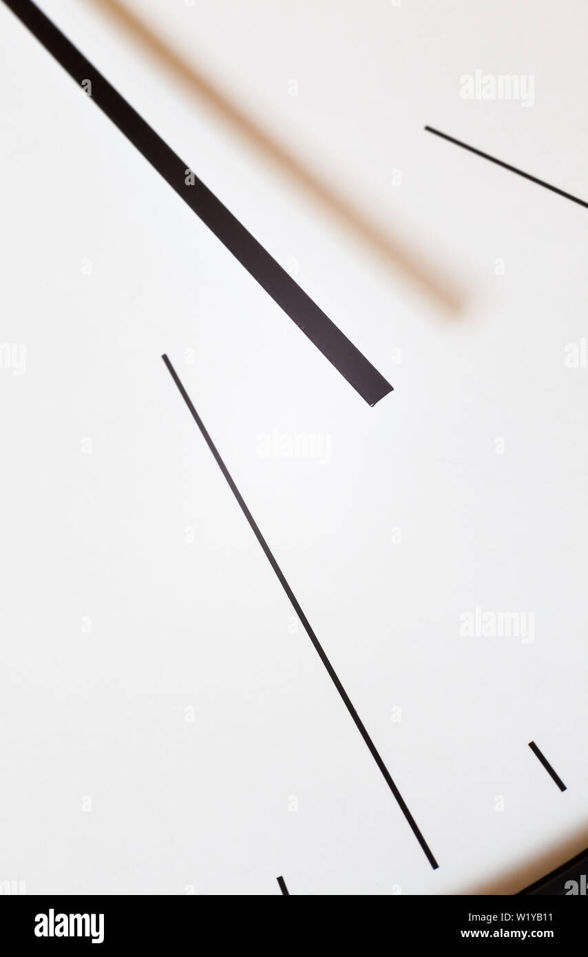 Closeup view of a simple wall watch, details of minute and hour hands on white background. Stock Photo