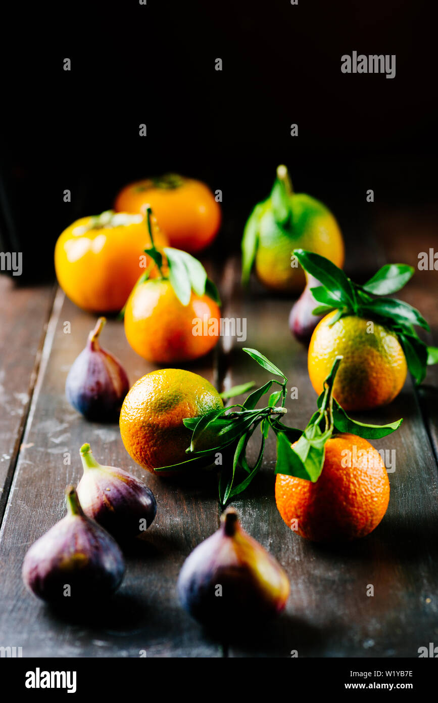 Satsuma Tangerine with Leaf on a wooden table, with fresh figs dark
