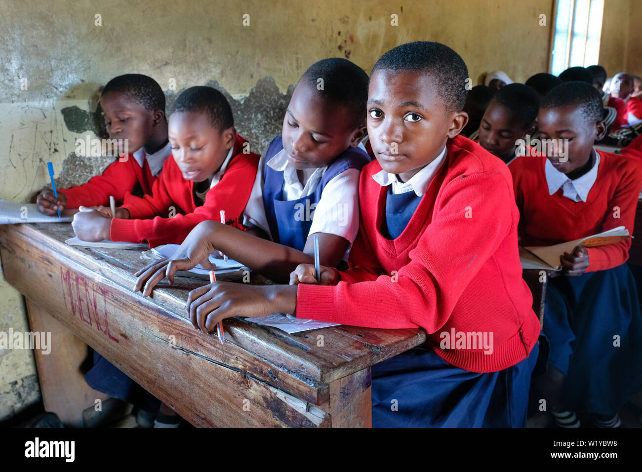 Students in red school uniforms in a school class of the Mwenge Primary School in Mbeya, Tanzania Stock Photo