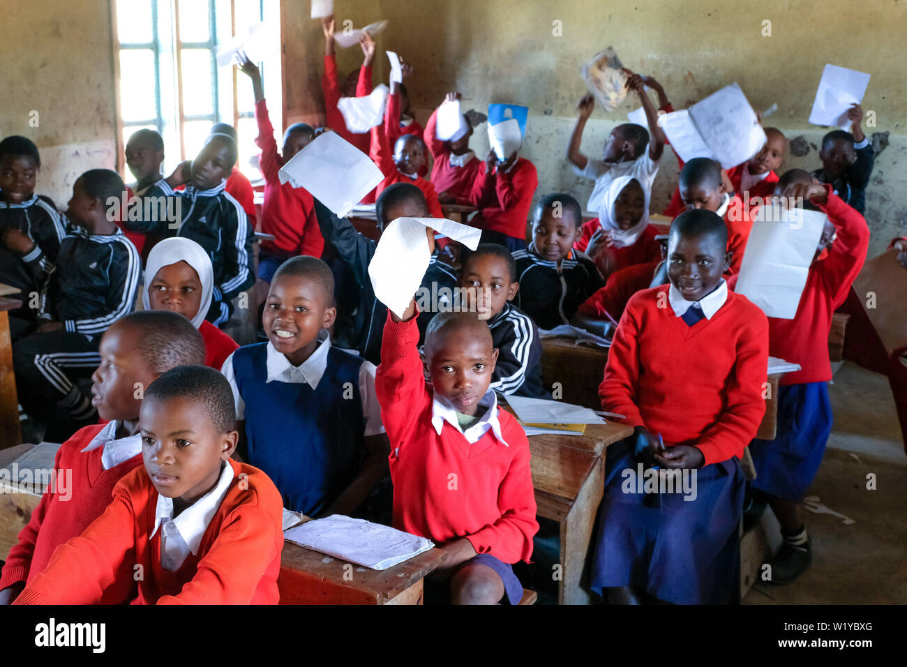 Students in red school uniforms in a school class of the Mwenge Primary School in Mbeya, Tanzania Stock Photo
