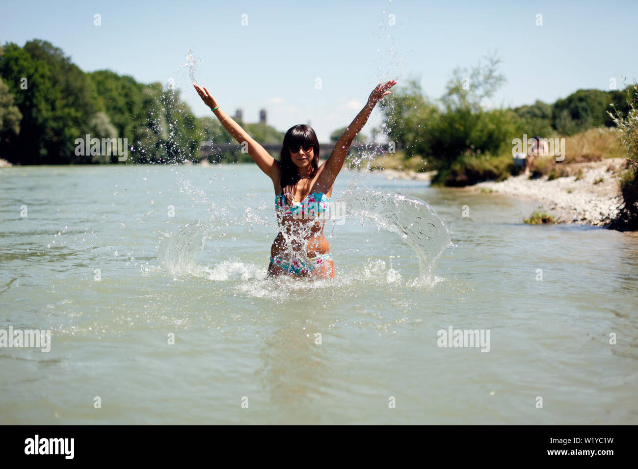 A young woman is bathing and splashing around and having fun in the isar, the beautiful river, which is flowing through munich Stock Photo