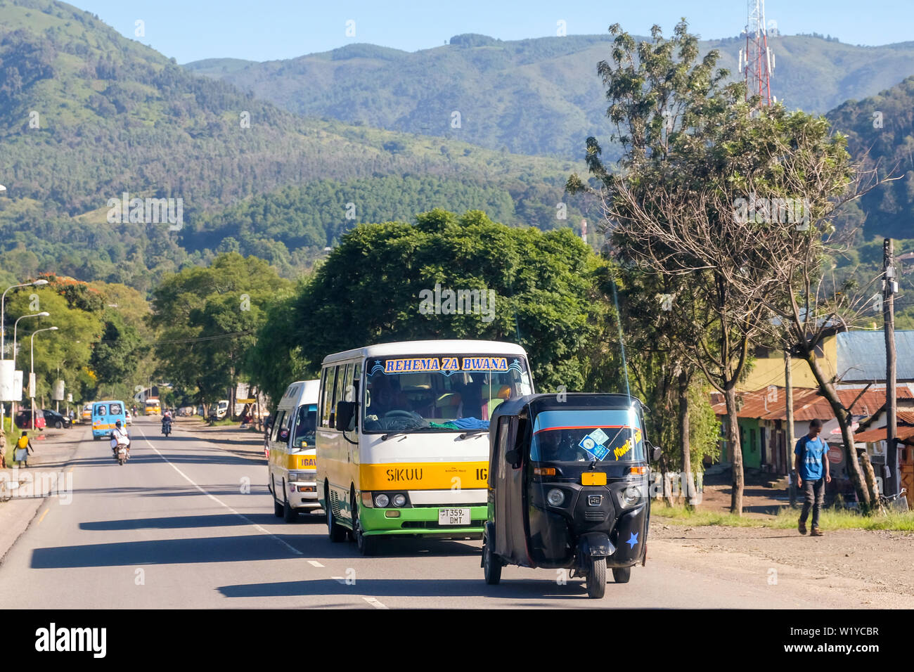 Tricycle taxi and bus in the streets of Mbeya, Tanzania.   ---   Dreirad-Taxi und Bus in den Straßen von Mbeya, Tansania. Stock Photo